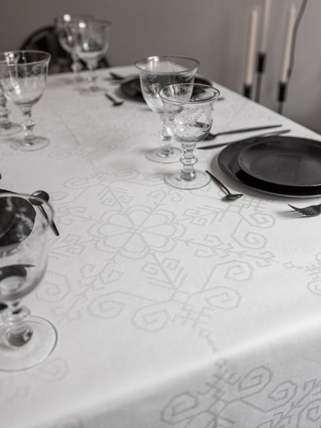 Balts taisnstūra austs žakarda kokvilnas galdauts ar latvju rakstu spēka zīmēm ar Saules mandalu